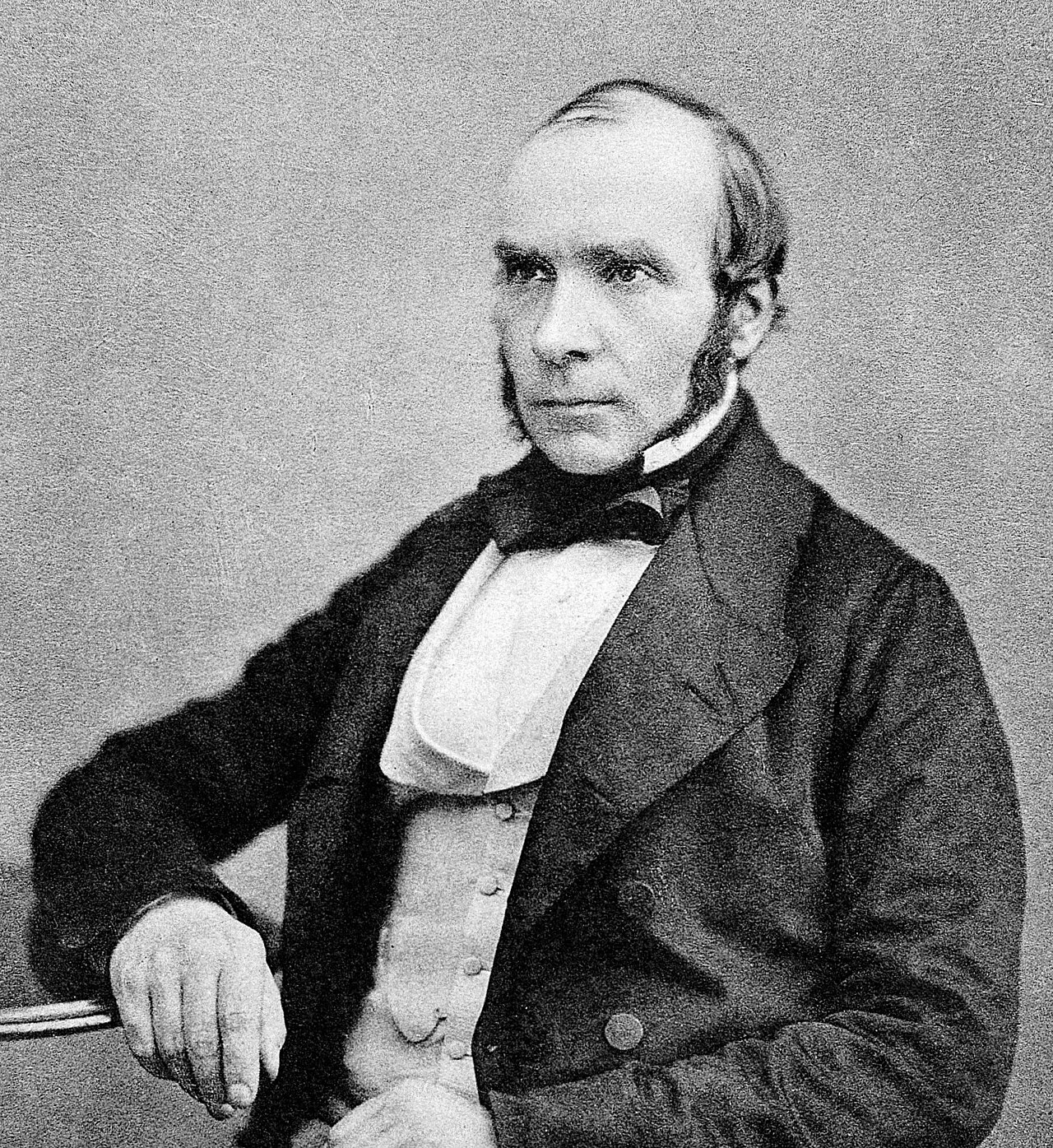 Retrato fotográfico do médico inglês John Snow, sentado e vestindo traje escuro.